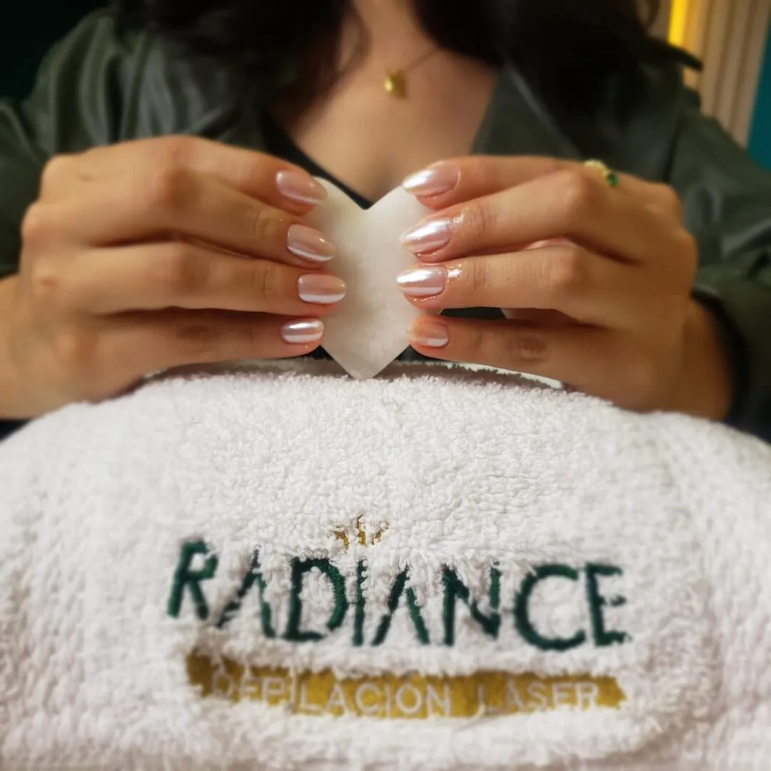 Manos formando un corazón sobre una toalla con el logo bordado de Radiance