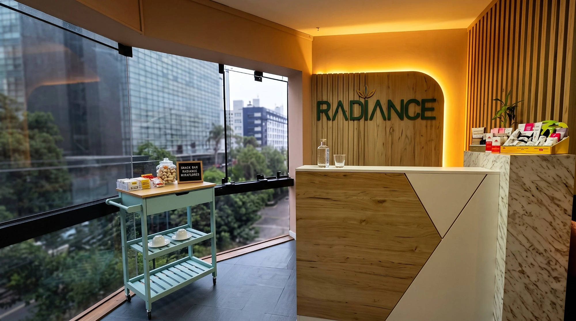 Recepción de Radiance Miraflores con el logo iluminado y el snack bar junto a la ventana